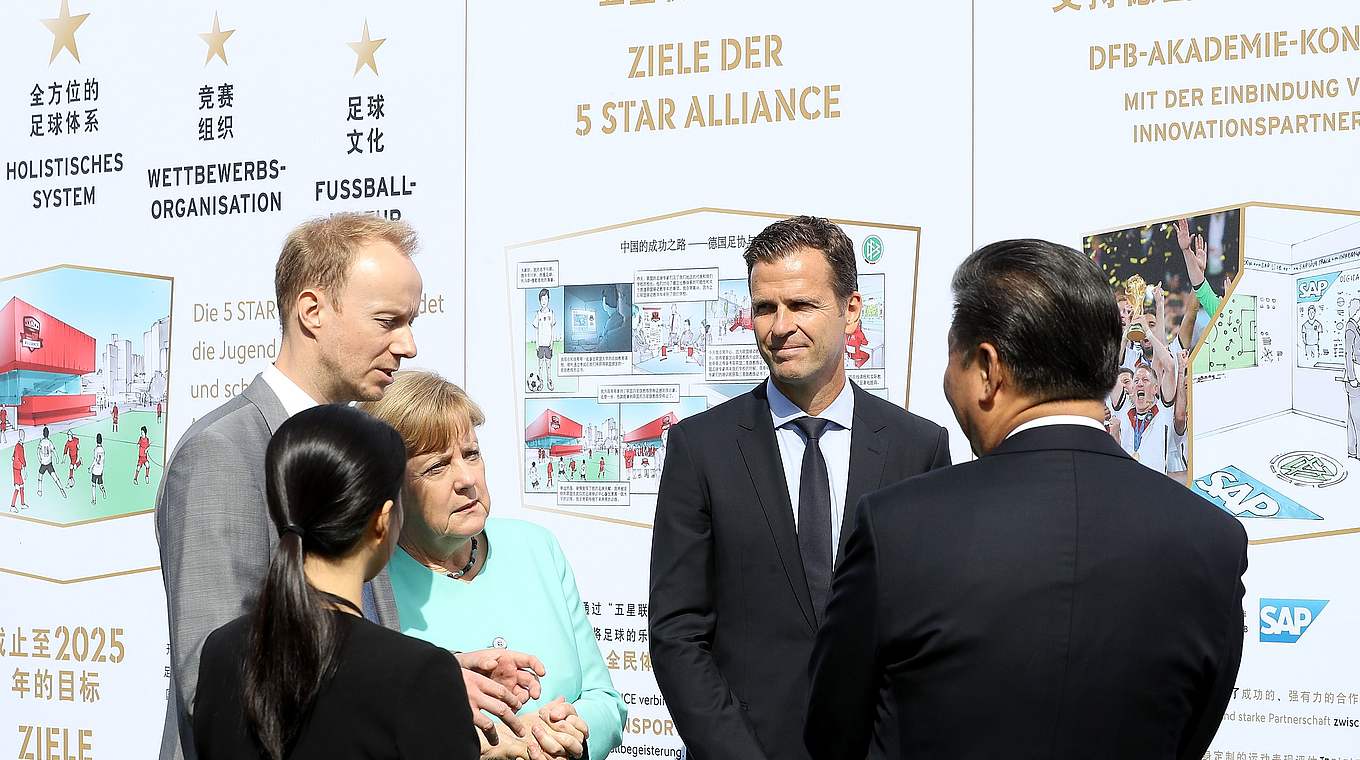 Merkel und Xi hören den Erklärungen von Nationalmannschafts-Manager Oliver Bierhoff zur DFB-Akademie zu.  © Getty Images