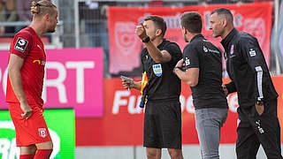 Diskussionen am Spielfeldrand: Halle-Profi Mai (l.) und Schiedsrichter Bacher (2.v.l.) © imago images/VIADATA