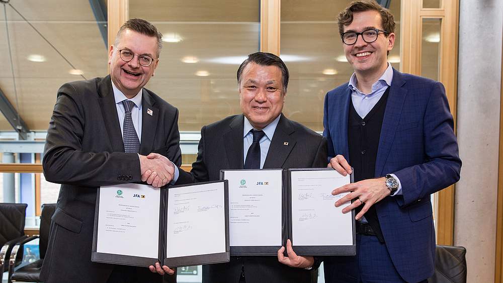 Verlängerung: Reinhard Grindel, Kohzo Tashima, Präsident der JFA, und Friedrich Curtius unterzeichnen 2018 ein neues MoU. © Getty Images