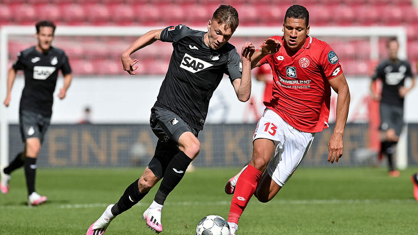  A photo of two soccer players in a match. The player on the left, in a black jersey, is Max Beier, a player for the German Bundesliga club Hoffenheim.